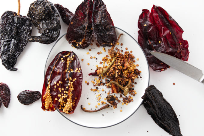 Dried chile peppers getting cut open and seeds removed.