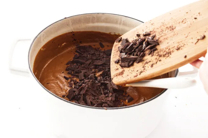 Adding chopped chocolate to a pot of mole sauce.
