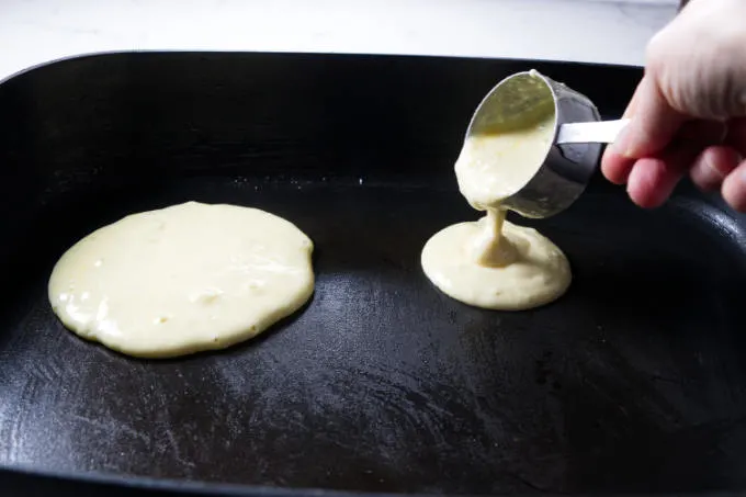 Pouring pancake batter on a hot griddle.