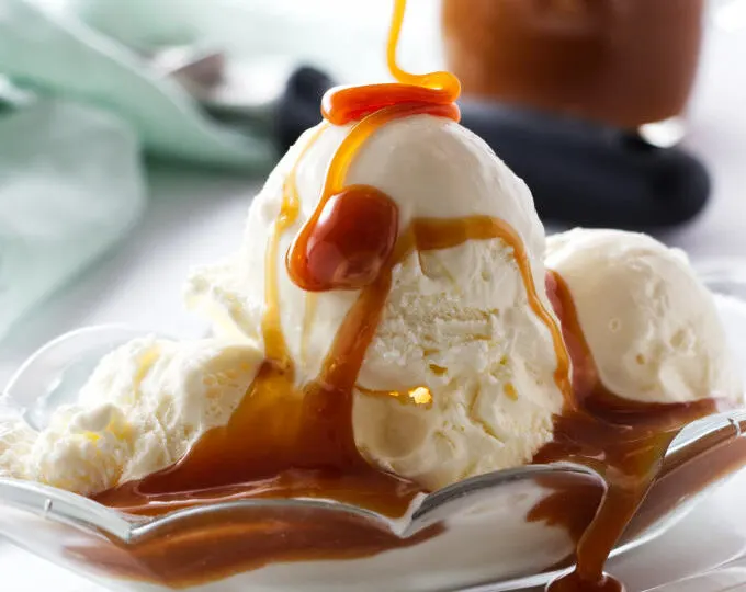 Drizzling caramel sauce over vanilla ice cream.