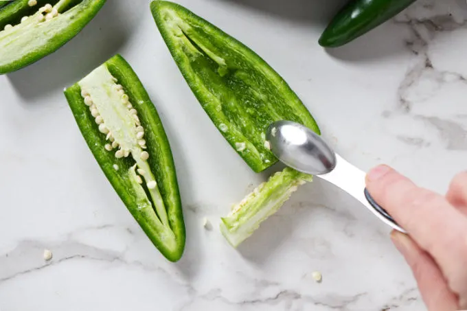 Scraping the white pith out of a jalapeno pepper.