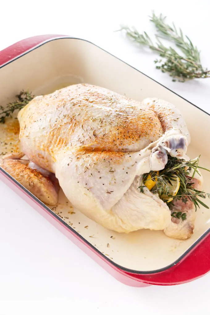 Chicken stuffed with herbs, garlic and lemon in a roasting pan