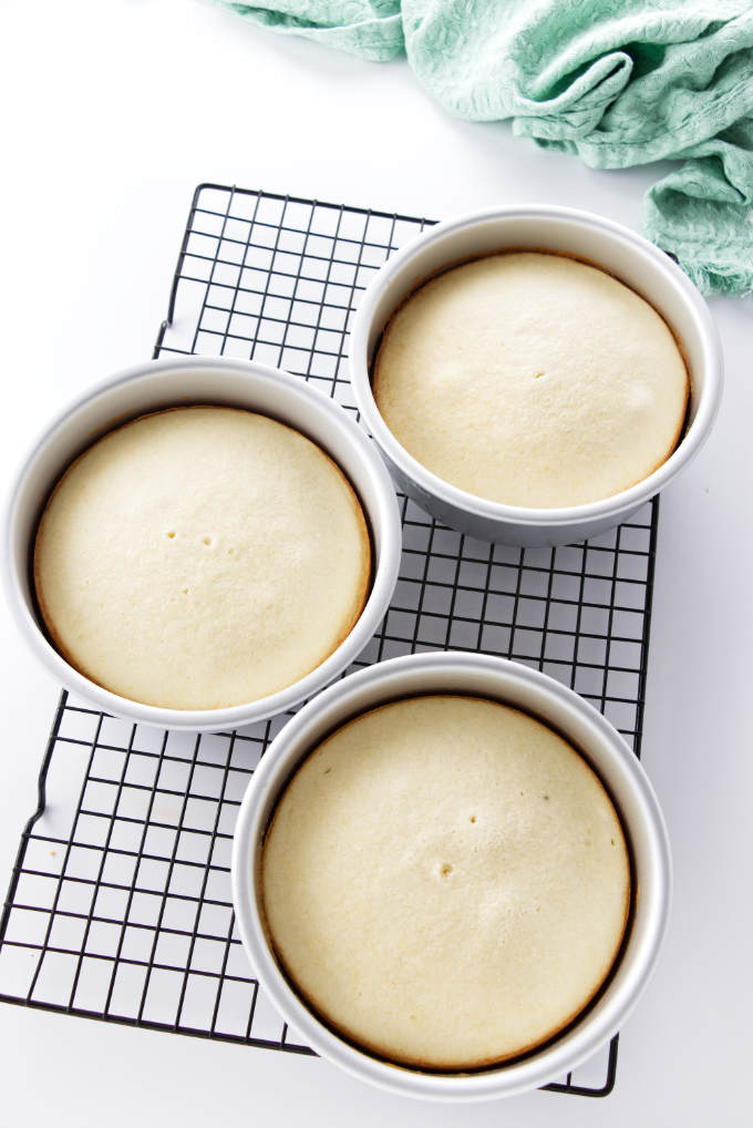 Three 6-inch cakes in pans on a cooling rack