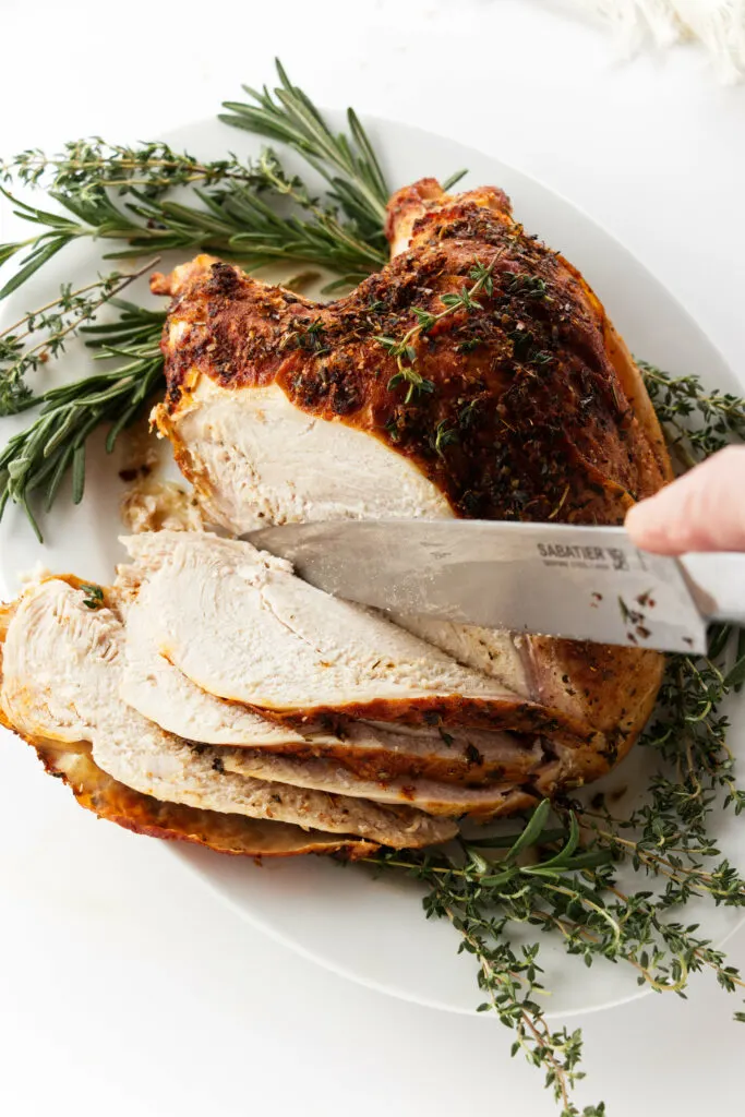 Turkey breast on a plate with knife slicing it
