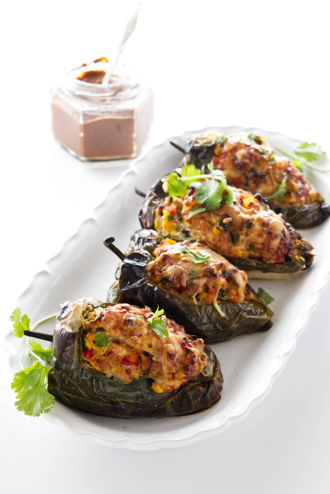 4 servings of chicken stuffed poblano peppers, mole sauce in a jar