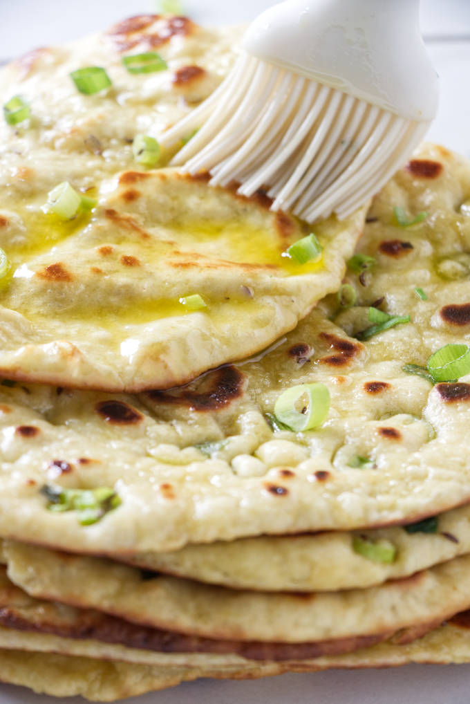 Brushing melted butter on naan bread.