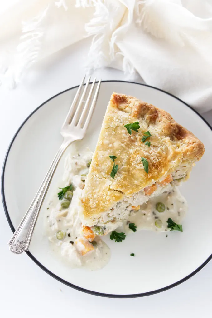 A slice of turkey pot pie on a plate with a fork.