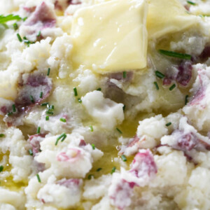Butter melting over a bowl of mashed red potatoes.