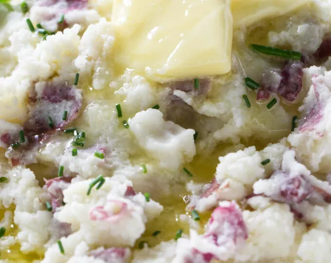 Butter melting over a bowl of mashed red potatoes.