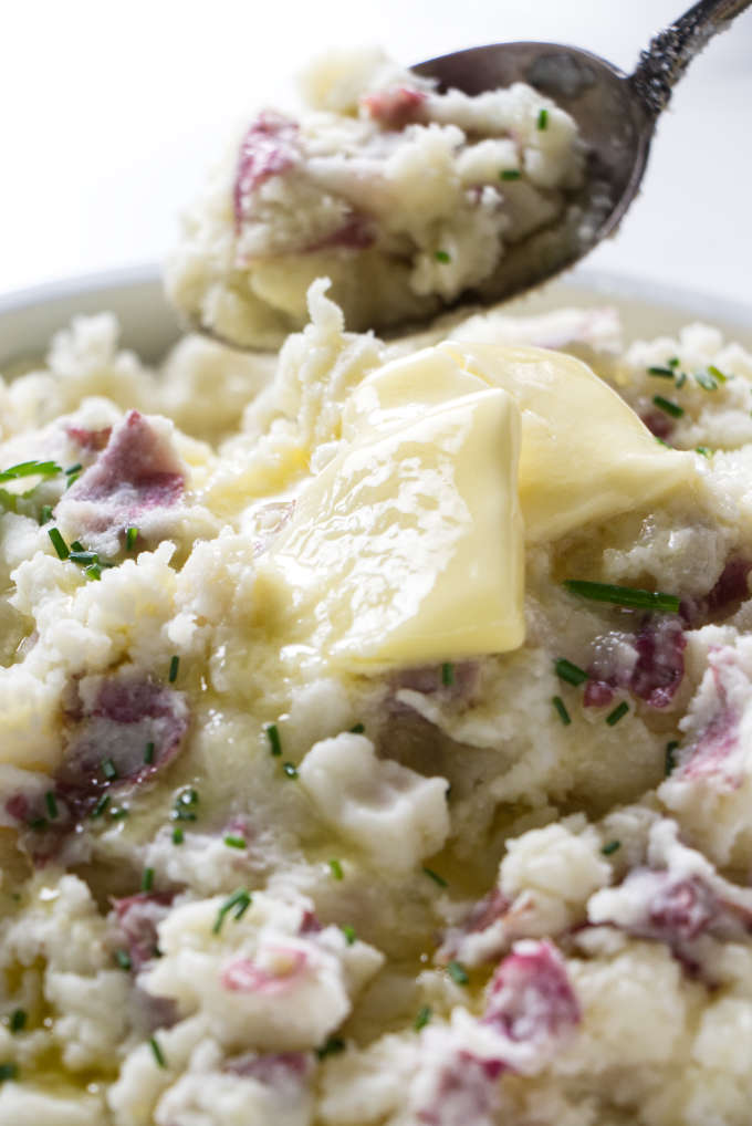 A spoon scooping up some mashed red potatoes.