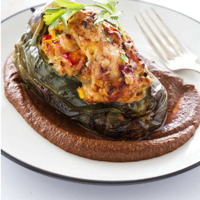 Baked poblano stuffed pepper on a puddle of mole sauce