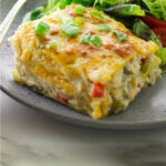 A slice of chicken casserole on a plate with a salad.