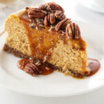 a slice of pumpkin cheesecake with pecans and caramel sauce