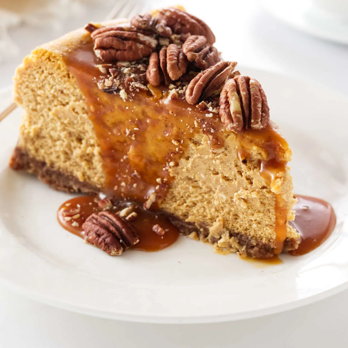 a slice of pumpkin cheesecake with pecans and caramel sauce