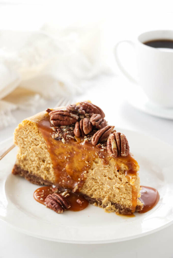 a slice of pumpkin cheesecake with pecans and caramel sauce