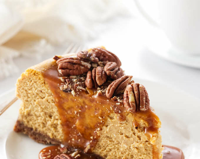 a slice of pumpkin cheesecake with pecans and caramel sauce