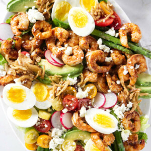 A large shrimp Louie salad next to Louie salad dressing.