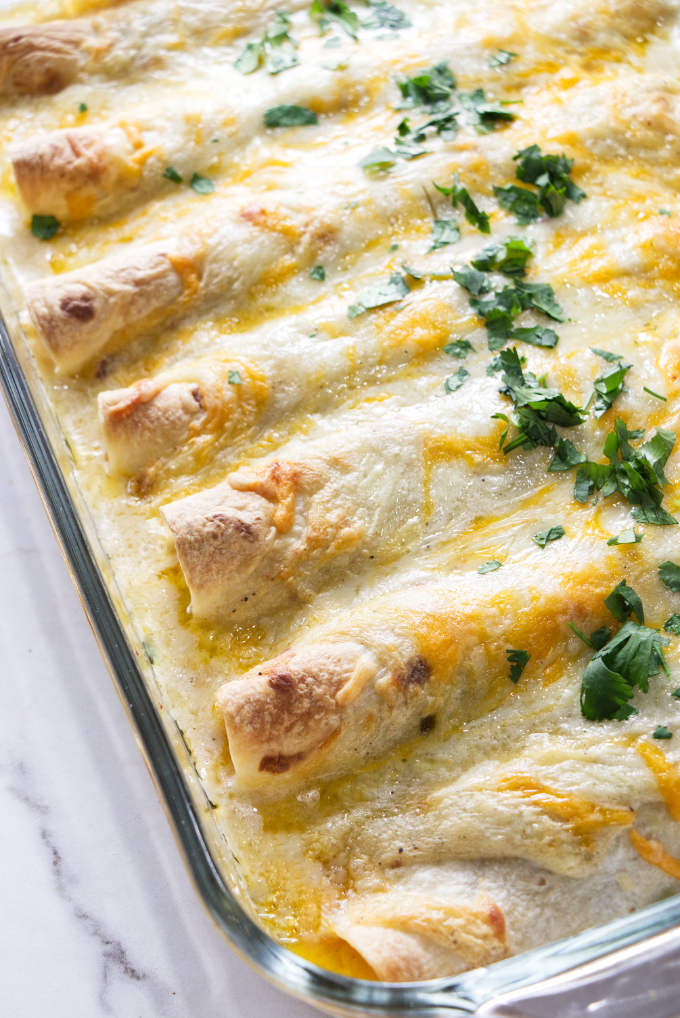 A casserole dish with white chicken enchiladas.