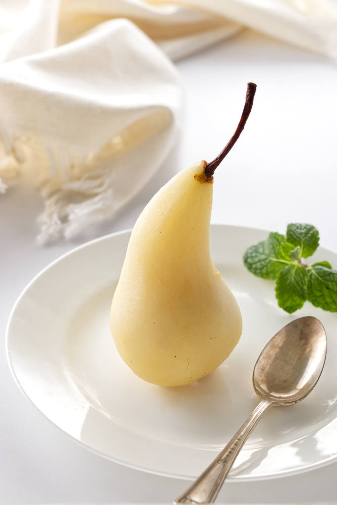White Wine Poached Pear on a serving plate with a spoon