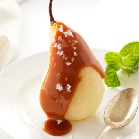 White wine poached pear covered with salted caramel sauce and flaky salt