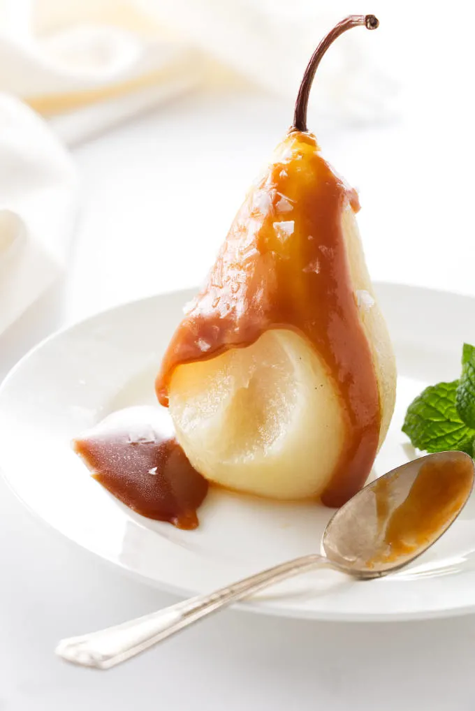 A serving of a White Wine Poached Pear with caramel sauce