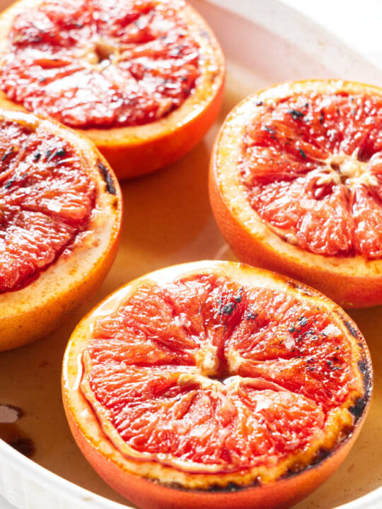 Four halves of grapefruit in a white baking dish.