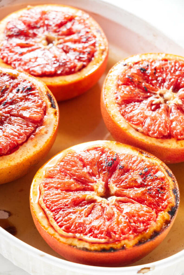 Four halves of grapefruit in a white baking dish.