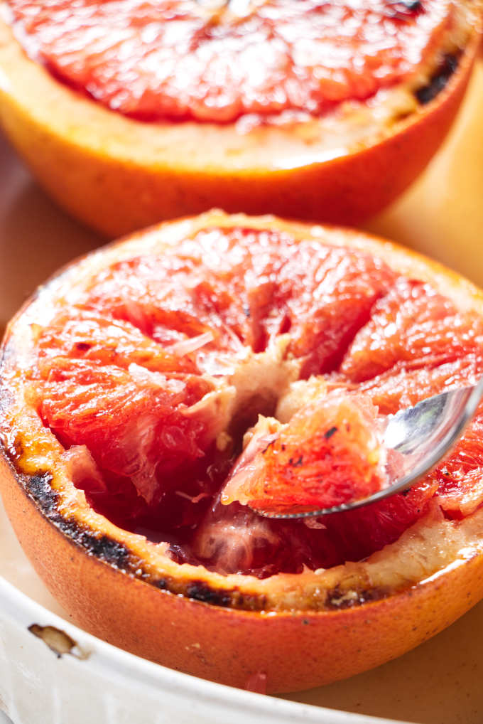 Scooping fruit out of a baked grapefruit.