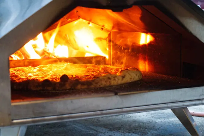 Cooking a pizza in a wood fired outdoor pizza oven.