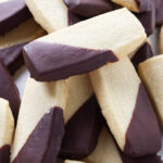 A large pile of shortbread cookies with chocolate coating.