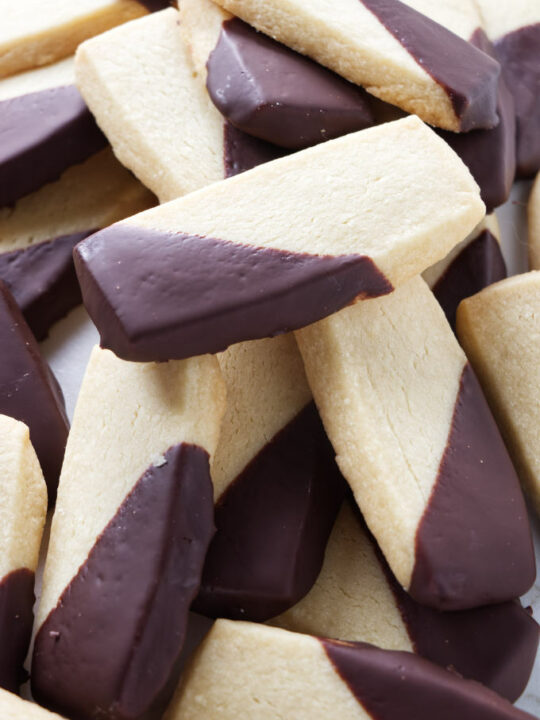 A large pile of shortbread cookies with chocolate coating.