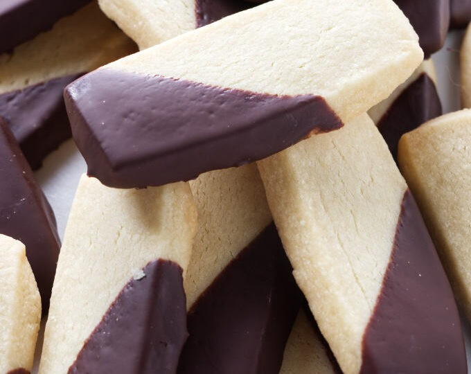 A large pile of shortbread cookies with chocolate coating.