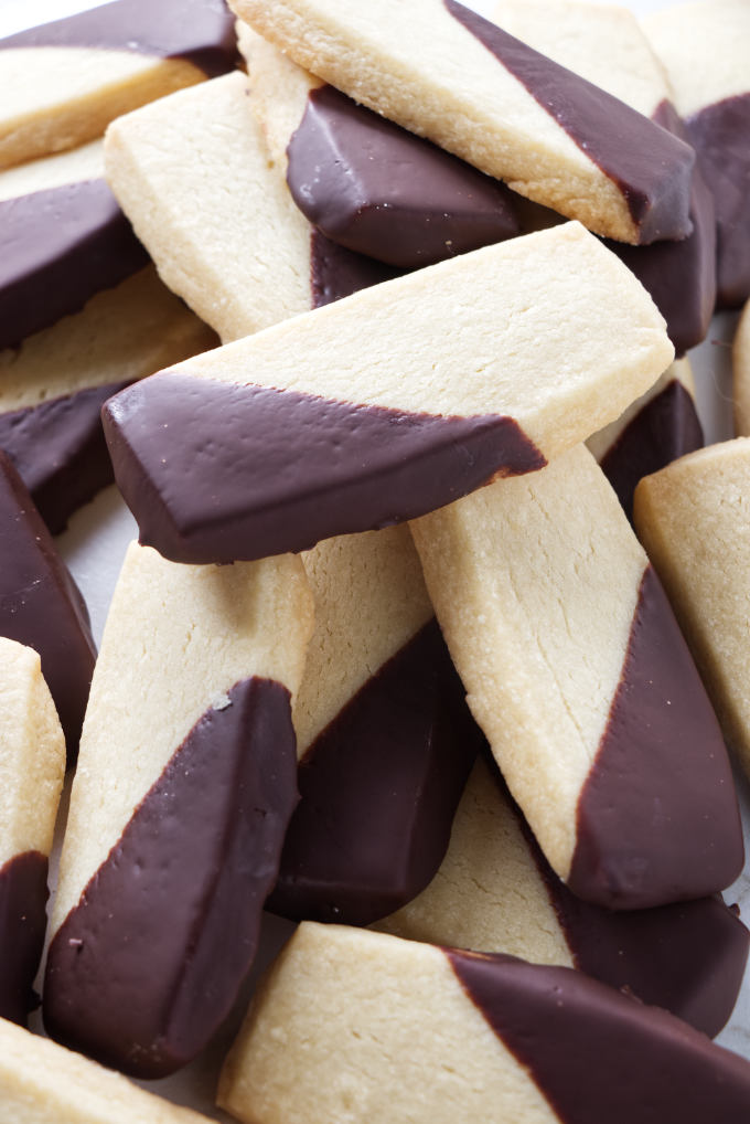 A large pile of shortbread cookies with chocolate coating.