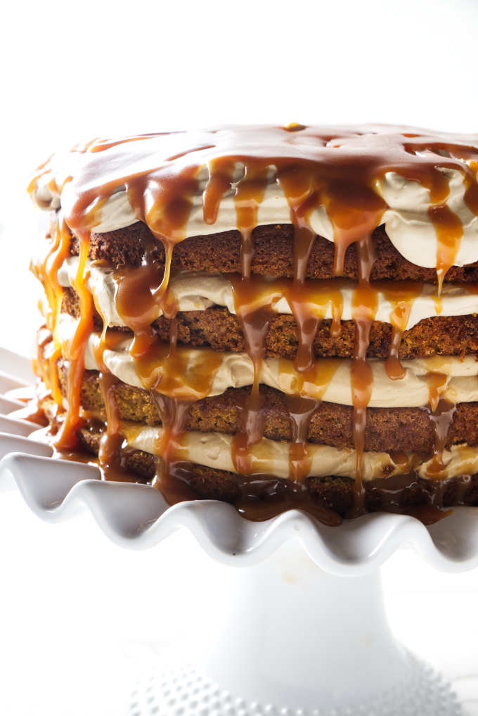 A four layer pumpkin cake with latte cream and caramel sauce dripping down the sides.