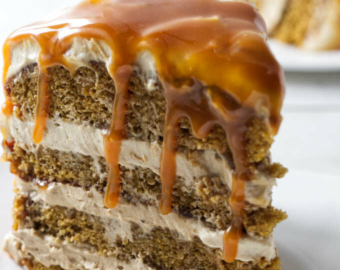 A pumpkin layer cake with caramel dripping off the top.