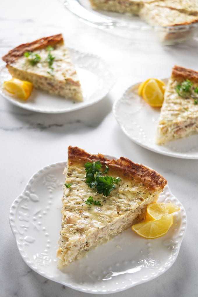 Three slices of salmon quiche on white plates.