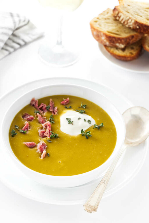 Overhead view of smoky split pea soup, glass of wine , napkin and bread in background