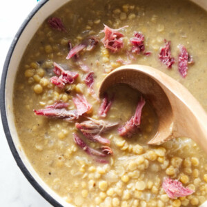 A pot of Swedish pea soup with yellow peas and shreds of ham hock meat on top.