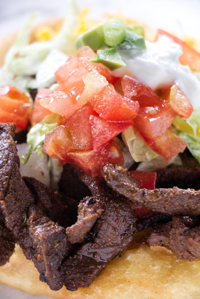 An Indian fry bread taco with steak strips.