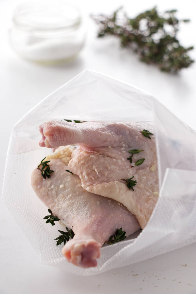 Duck legs in a sous vide bag, salt and thyme in background