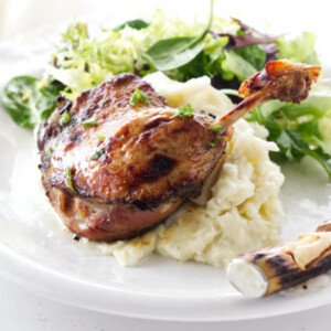 Plated serving of Sous Vide Duck Leg Confit on mashed potatoes and salad