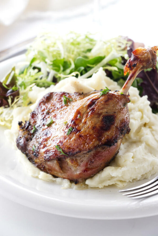 Serving of duck leg confit with mashed potatoes and salad