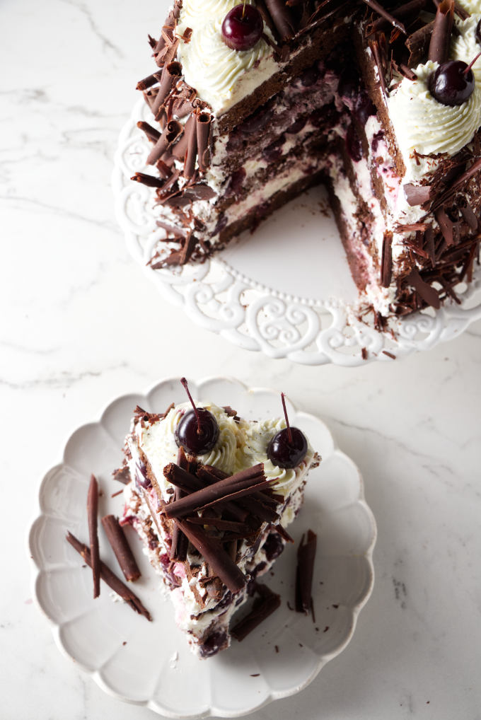 A cake slice next to a cake on a cake plate.