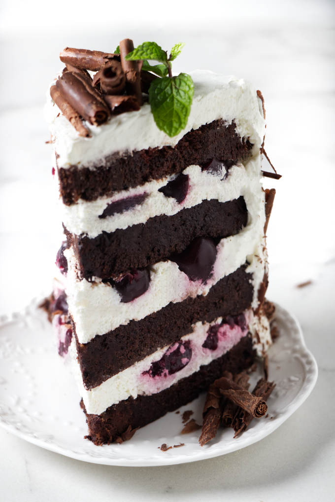 A slice of black forest layer cake with four layers.