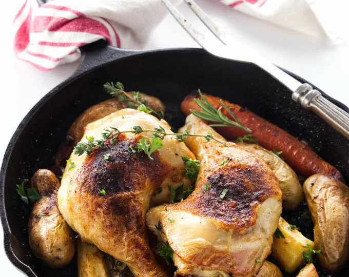 Two chicken quarters in a cast iron skillet.