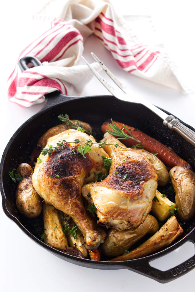 Two chicken quarters in a cast iron skillet.
