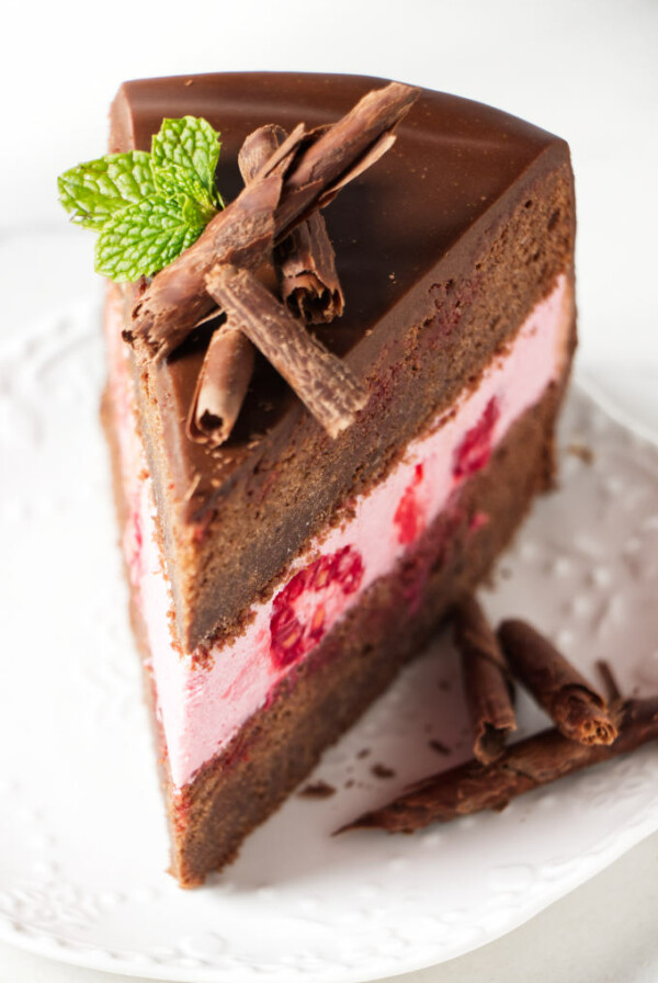 A slice of chocolate sponge cake filled with raspberry mousse cake filling.