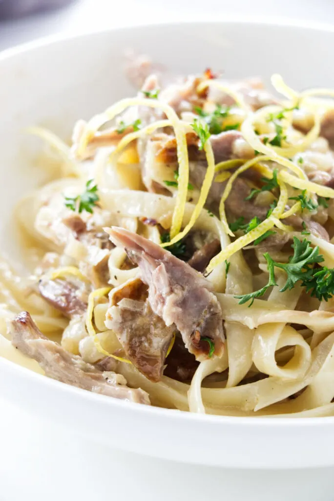 close up of duck pasta garnished with lemon zest and parsley