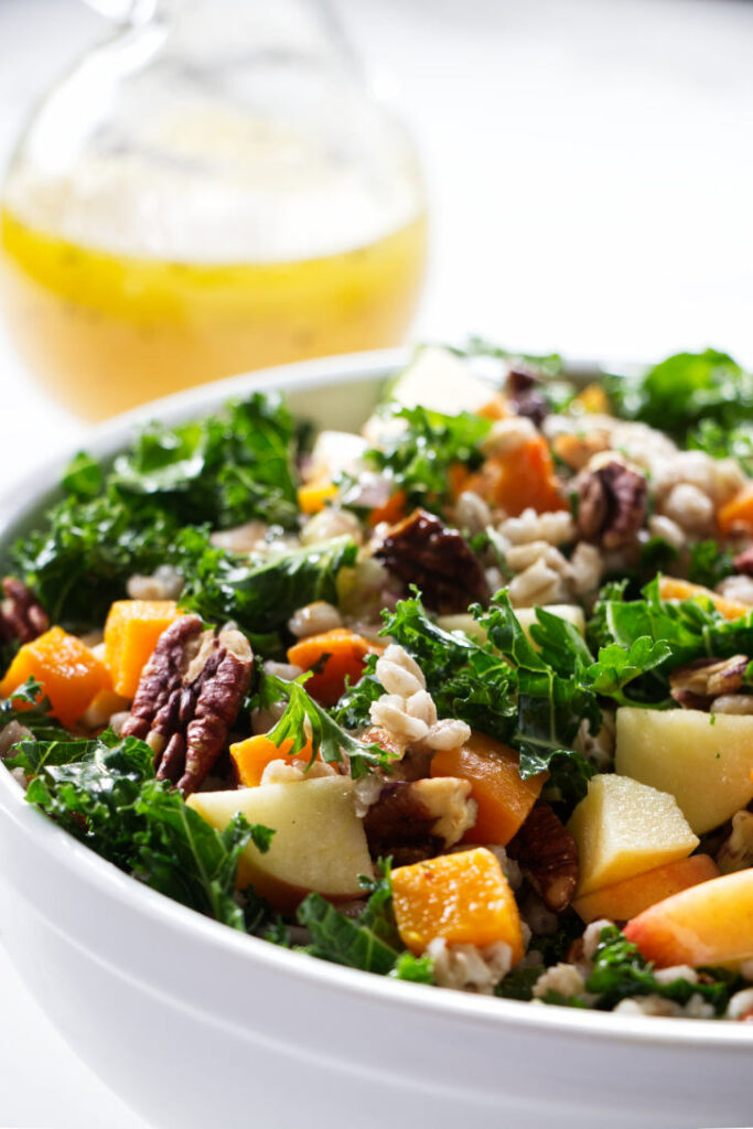 Kale salad with chunks of squash, barley, apple, and pecans.