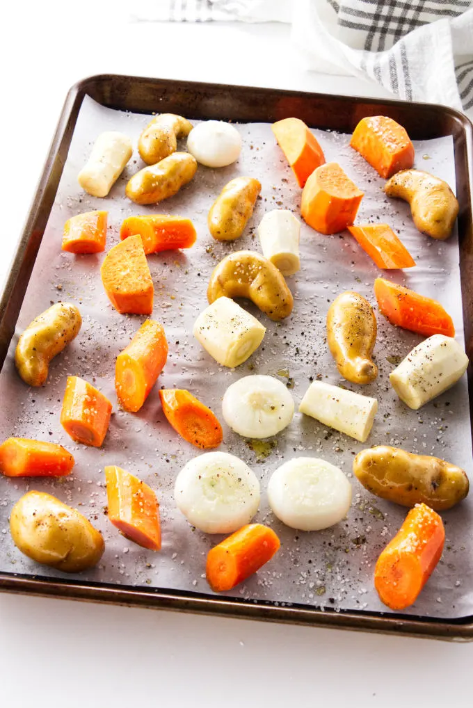 Seasoned root vegetables on a baking sheet ready for the oven.